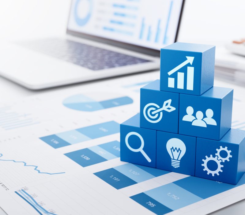 Business strategy for marketing and management. Stacked blue blocks, reports and laptop.