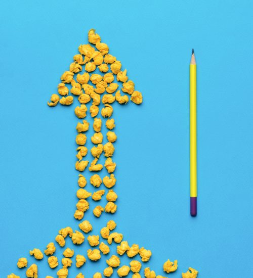 Minimal business concept. A rising arrow made of pieces of crumpled paper and a pencil on a blue background. Flat lay. Minimal business concept. A rising arrow made of pieces of crumpled paper and a pencil on a blue background. A symbol of an idea. Flat lay.